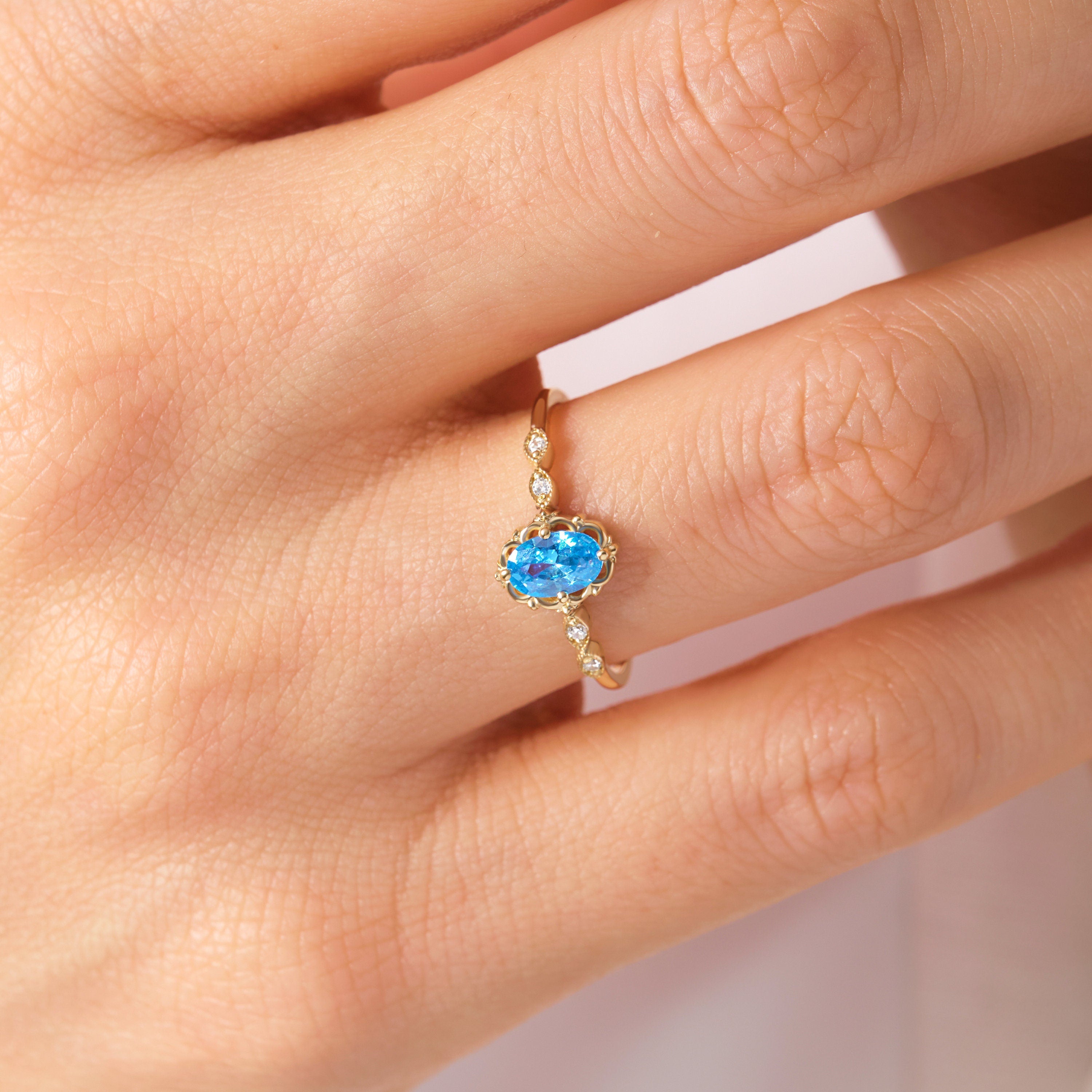 Oval Blue Topaz Engagement Ring – 14K Solid Gold Lace Band 💙✨
Delicate, radiant, and full of charm — this Oval Blue Topaz Engagement Ring brings a touch of the sky to your hand. Expertly crafted in solid 14K gold, it features a 6x4 mm oval-cut blue topaz, symbolizing peace and loyalty, surrounded by sparkling moissanites or diamonds on a graceful lace-inspired band.