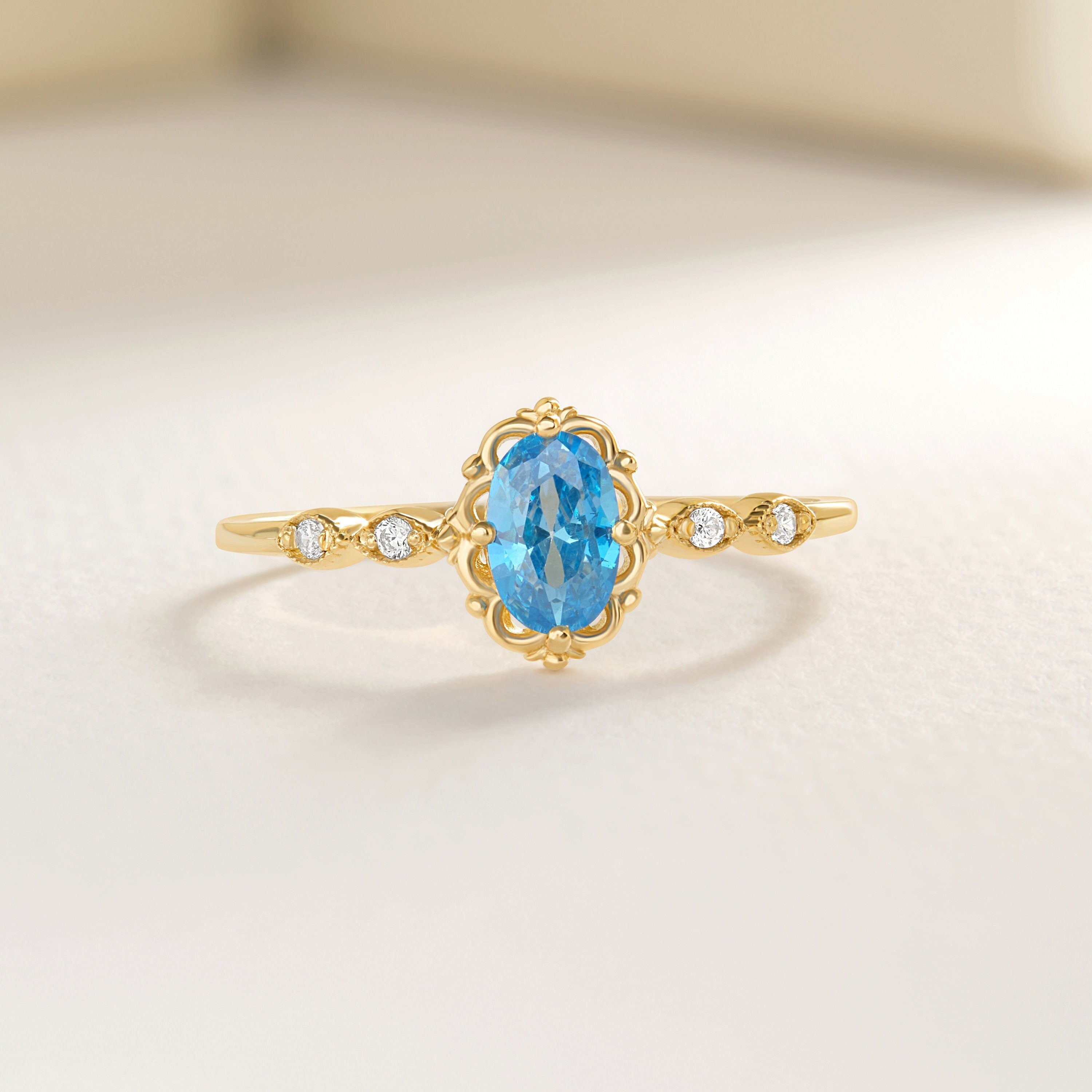 Oval Blue Topaz Engagement Ring – 14K Solid Gold Lace Band 💙✨
Delicate, radiant, and full of charm — this Oval Blue Topaz Engagement Ring brings a touch of the sky to your hand. Expertly crafted in solid 14K gold, it features a 6x4 mm oval-cut blue topaz, symbolizing peace and loyalty, surrounded by sparkling moissanites or diamonds on a graceful lace-inspired band.
