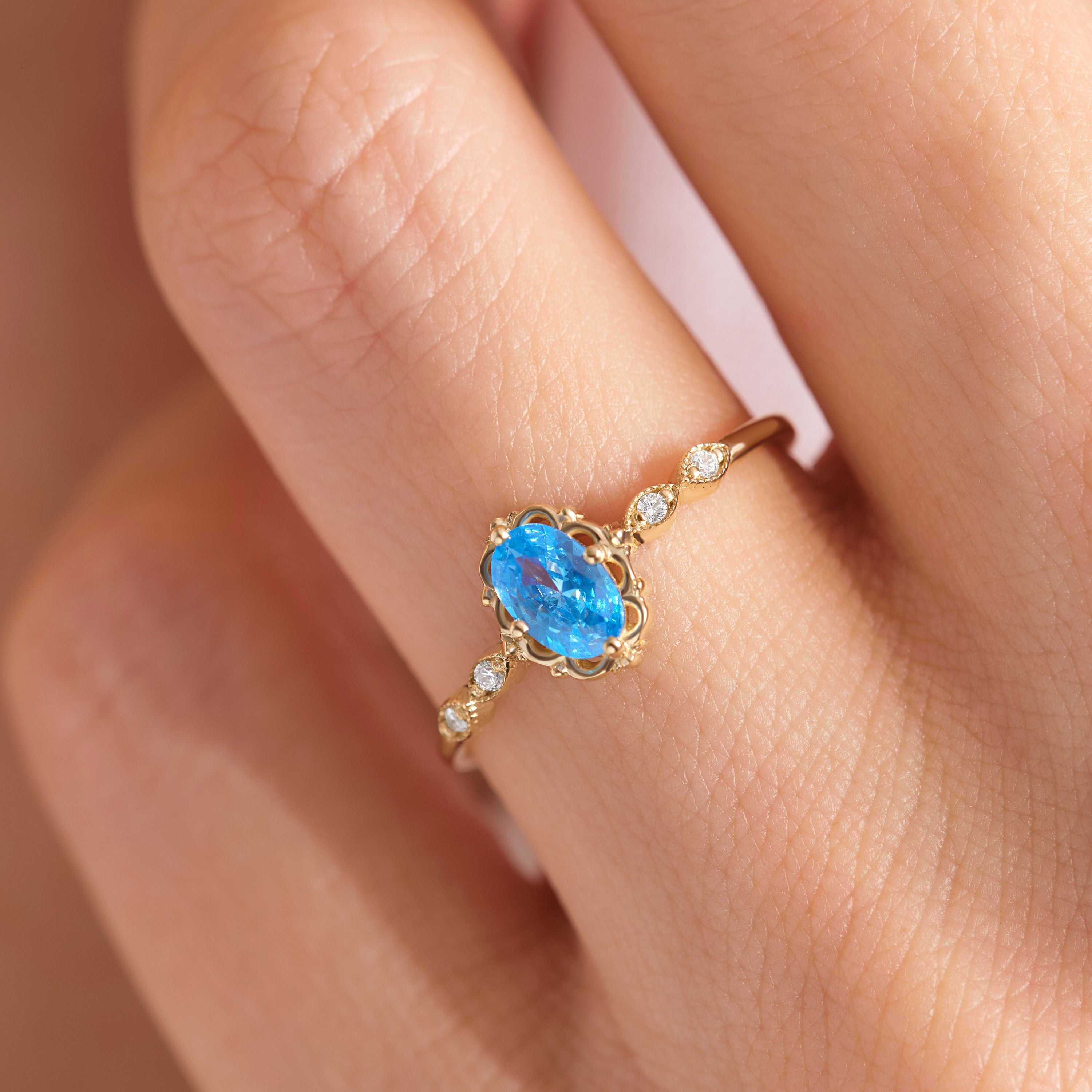 Oval Blue Topaz Engagement Ring – 14K Solid Gold Lace Band 💙✨
Delicate, radiant, and full of charm — this Oval Blue Topaz Engagement Ring brings a touch of the sky to your hand. Expertly crafted in solid 14K gold, it features a 6x4 mm oval-cut blue topaz, symbolizing peace and loyalty, surrounded by sparkling moissanites or diamonds on a graceful lace-inspired band.
