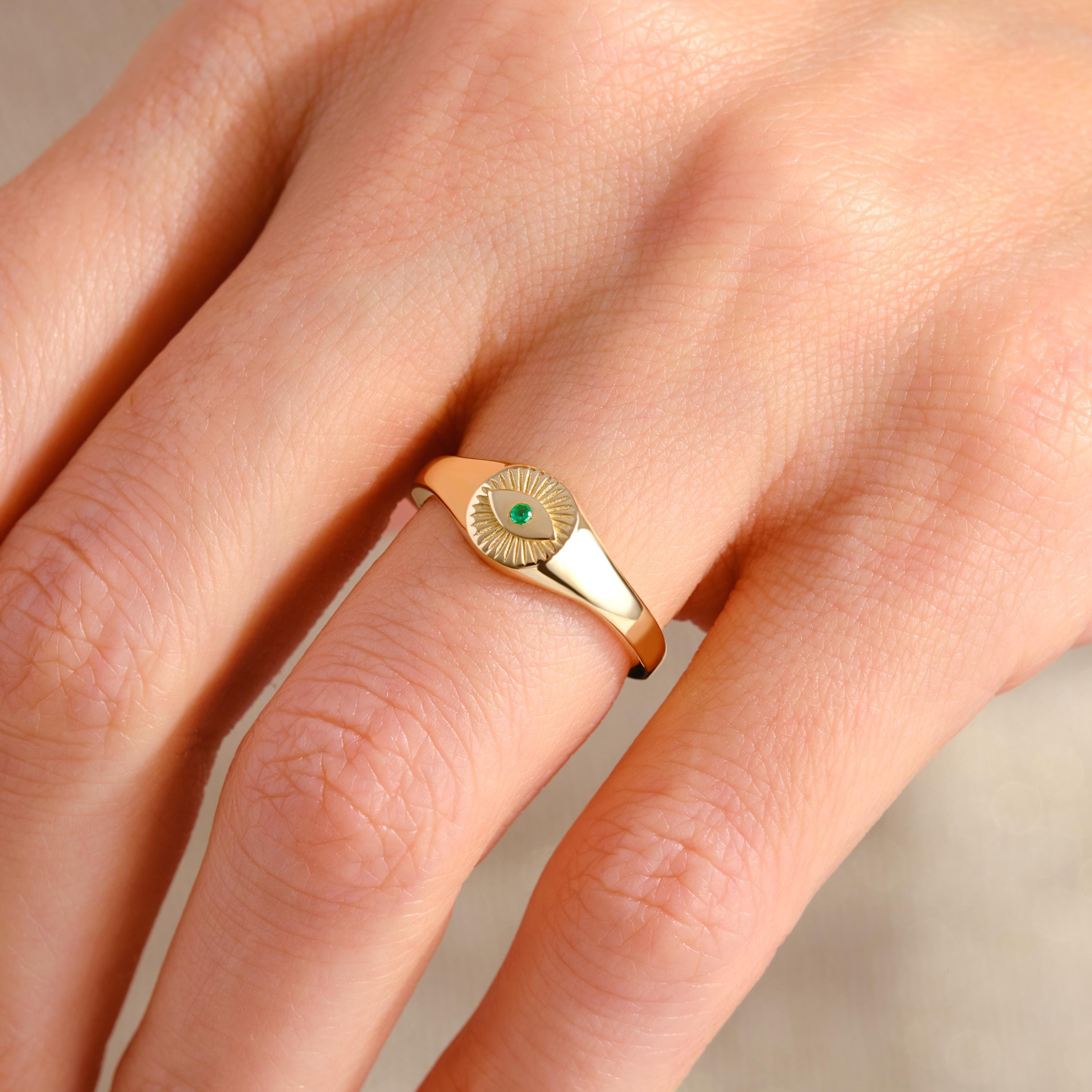 ChatGPT:

💚 Emerald Eye Signet Ring – 14K Solid Gold Bezel Set Evil Eye Dome Band 💍

Protective, elegant, and full of symbolism — this Emerald Eye Signet Ring brings a modern twist to the ancient evil eye design. Crafted from solid gold and featuring a brilliant green cubic zirconia stone, this dainty yet bold piece radiates both style and meaning. Perfect as a pinky ring, everyday statement, or symbolic gift of protection.