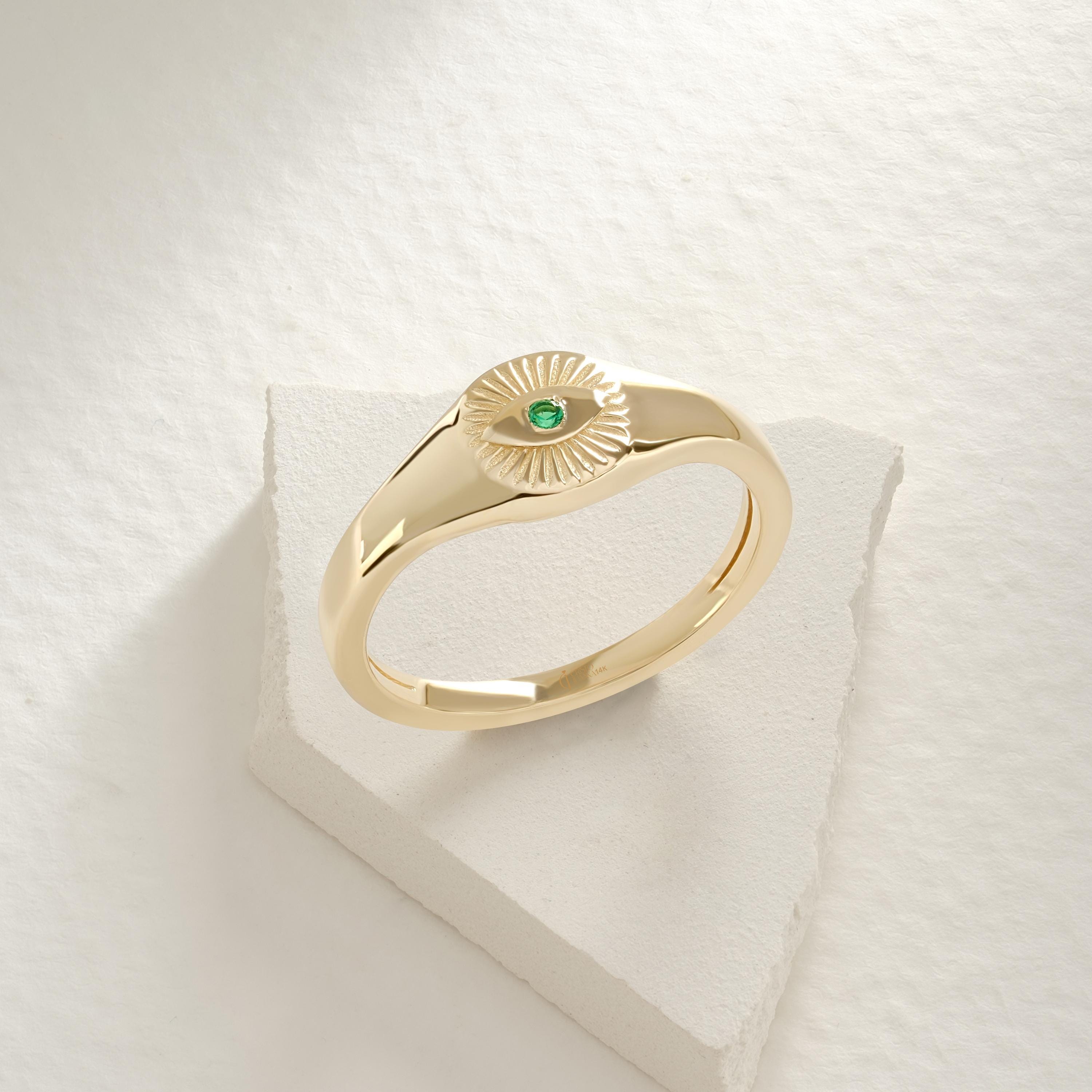 ChatGPT:

💚 Emerald Eye Signet Ring – 14K Solid Gold Bezel Set Evil Eye Dome Band 💍

Protective, elegant, and full of symbolism — this Emerald Eye Signet Ring brings a modern twist to the ancient evil eye design. Crafted from solid gold and featuring a brilliant green cubic zirconia stone, this dainty yet bold piece radiates both style and meaning. Perfect as a pinky ring, everyday statement, or symbolic gift of protection.