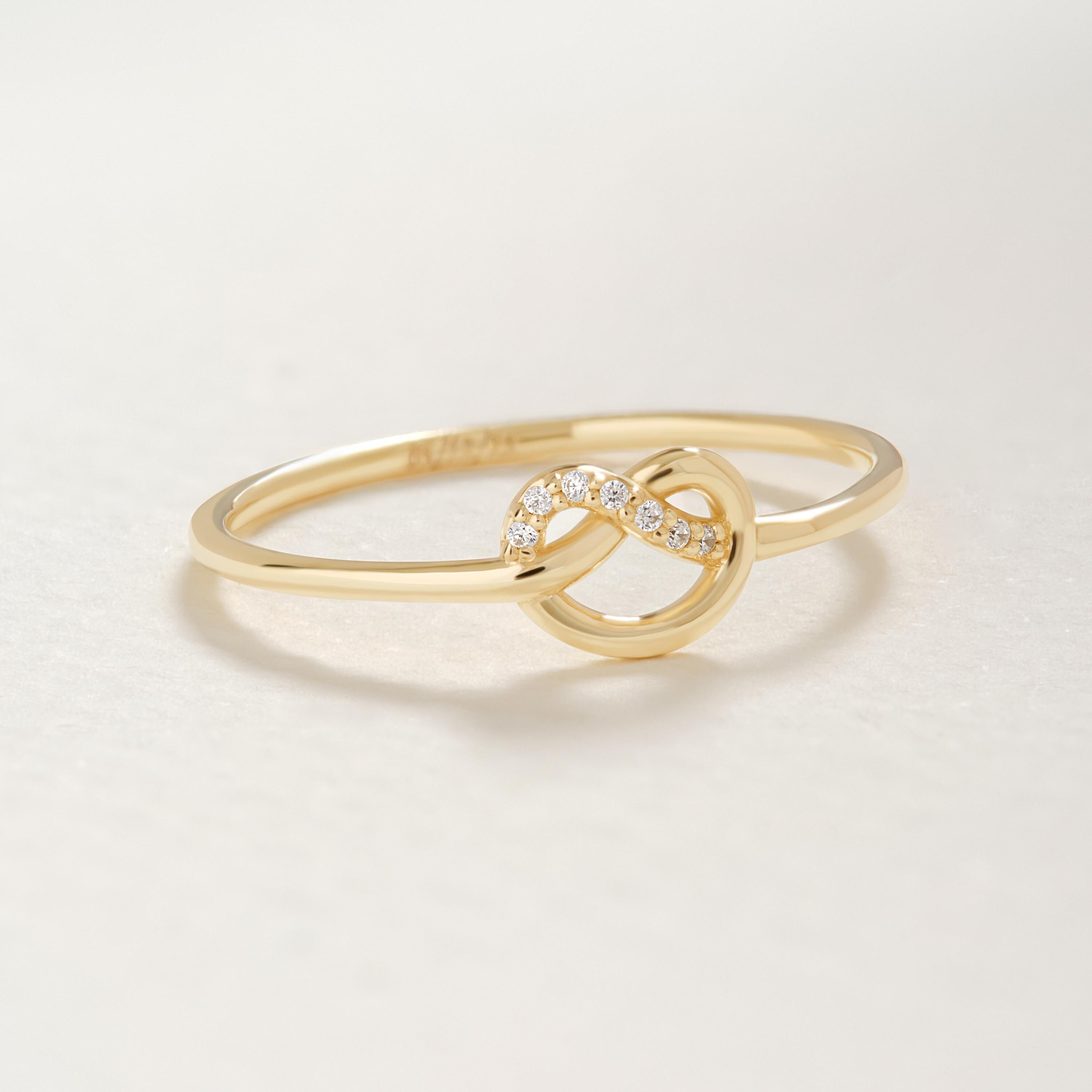 Love Knot Wedding Ring – 14K Solid Gold ✨💖
This delicate love knot ring features 7 tiny round-cut diamonds set along a dainty gold band — a timeless symbol of connection, unity, and unbreakable bonds. Perfect as a wedding promise ring, soulmate gift, or a meaningful token for your best friend.

Its minimalist heart-knot design is both elegant and symbolic, ideal for everyday wear or stacking.