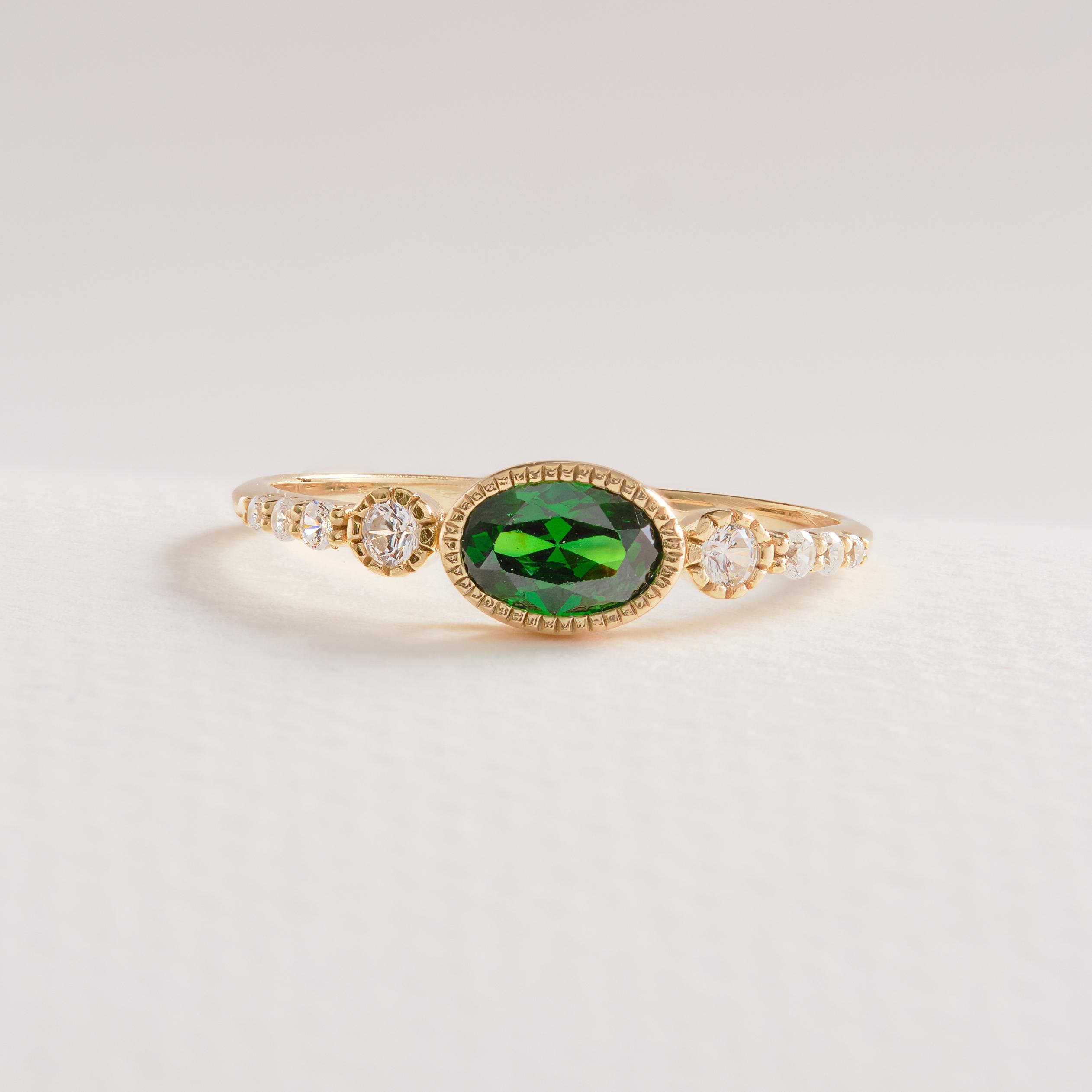 💚 Vintage Inspired Emerald Ring | Oval Birthstone Ring with Side Diamonds – 14K Solid Gold

This vintage inspired emerald ring showcases a timeless Art Deco elegance, featuring a glowing oval-cut green gemstone framed in a sleek bezel setting and accented with sparkling side stones. Handcrafted in solid gold, this ring blends classic charm with modern craftsmanship—perfect for meaningful moments and everyday luxury.