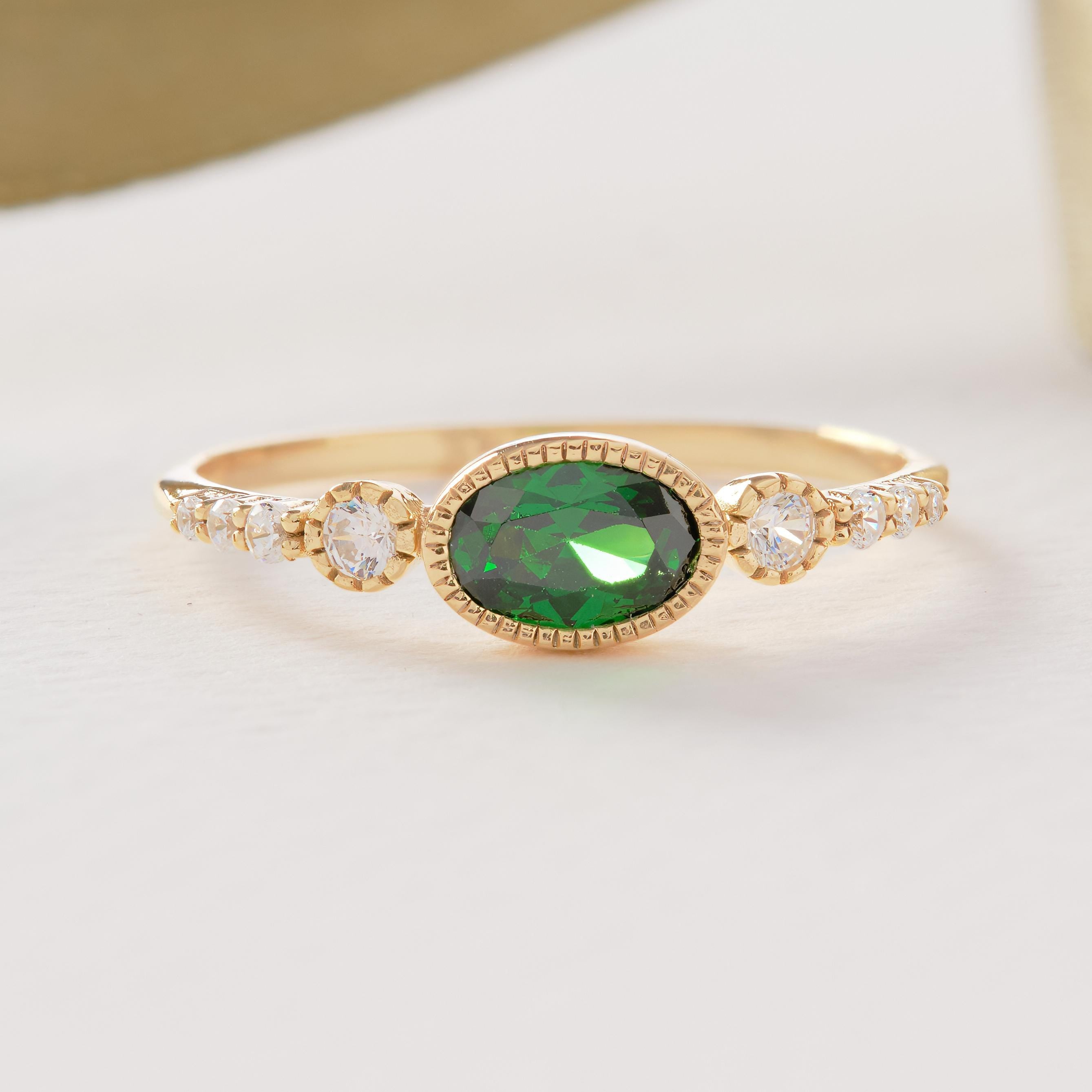 💚 Vintage Inspired Emerald Ring | Oval Birthstone Ring with Side Diamonds – 14K Solid Gold

This vintage inspired emerald ring showcases a timeless Art Deco elegance, featuring a glowing oval-cut green gemstone framed in a sleek bezel setting and accented with sparkling side stones. Handcrafted in solid gold, this ring blends classic charm with modern craftsmanship—perfect for meaningful moments and everyday luxury.